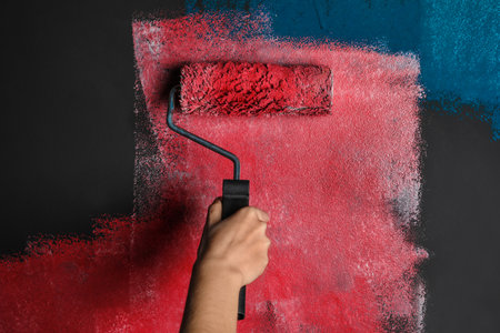 Woman painting gray wall with pink dye, closeup