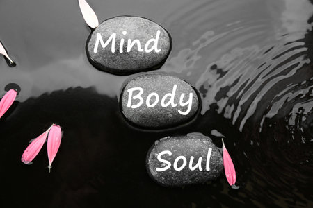 Spa stones with words Mind, Body, Soul and pink flower petals in water, flat lay. Zen lifestyleの写真素材