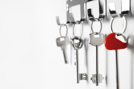 Metal key holder on light wall indoors, closeup. Space for textの写真素材