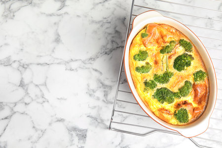 Tasty broccoli casserole in baking dish on cooling rack, top view. Space for textの写真素材