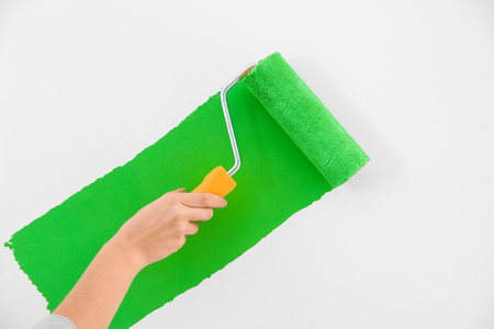 Woman painting white wall with green dye, closeup. interior renovationの写真素材