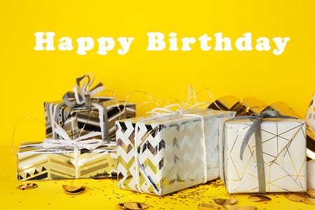 Gift boxes and text Happy Birthday on yellow backgroundの写真素材