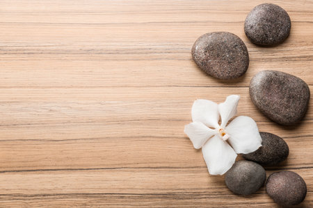Stones and orchid flower on wooden background, top view with space for text. Zen lifestyleの写真素材
