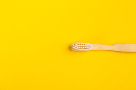 Toothbrush made of bamboo on yellow background, top view. Space for textの写真素材