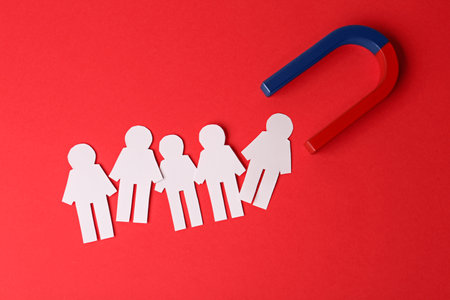 Magnet and paper people on red background, flat lay