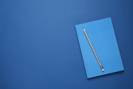 Notebook and pencil on bright background, top view with space for text. Color of the year 2020...