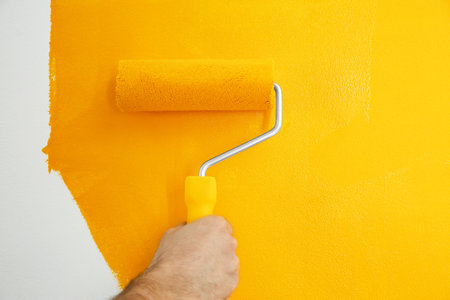 Man painting white wall with yellow dye, closeup. interior renovationの写真素材