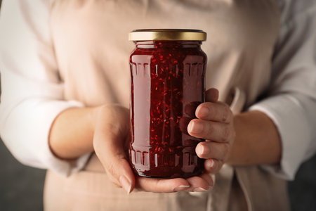 Woman with jar of raspberry jam, closeupの写真素材