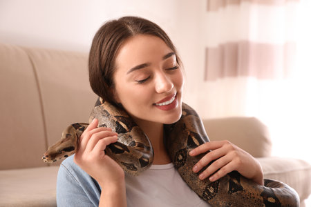 Young woman with her boa constrictor at home. Exotic pet