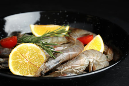 Fresh raw shrimps with lemon slices on black table, closeupの写真素材
