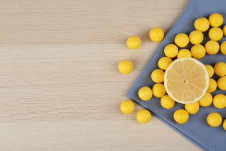 Flat lay composition with tasty lemon drops on wooden table. Space for text