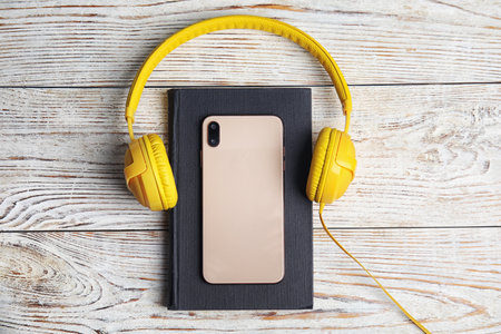 Book, modern headphones and smartphone on white wooden table, flat layの写真素材