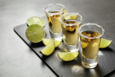 Mexican Tequila shots with salt and lime slices on gray tableの写真素材