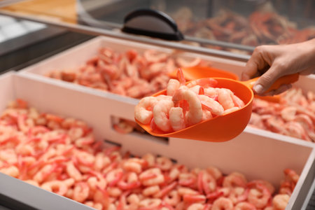 Woman holding shovel with frozen shrimps in store, closeup. wholesale marketの写真素材