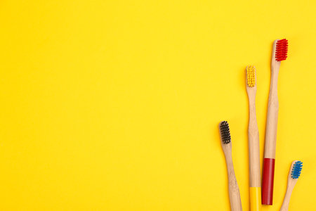 Toothbrushes made of bamboo on yellow background, flat lay. Space for textの写真素材
