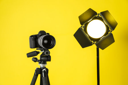 Professional video camera and lighting equipment on yellow backgroundの写真素材