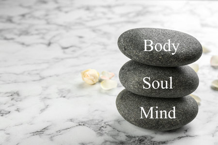 Stones with words MIND, BODY, SOUL on marble background, space for text. Zen lifestyleの写真素材