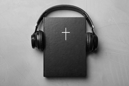 Bible and headphones on light gray background, top view. religious audiobook