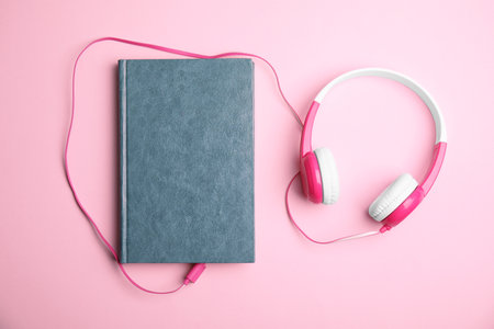 Book and modern headphones on pink background, flat layの写真素材