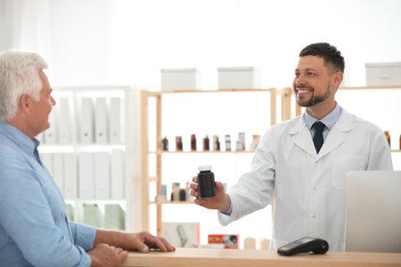 Pharmacist giving medicine to customer in drugstoreの写真素材