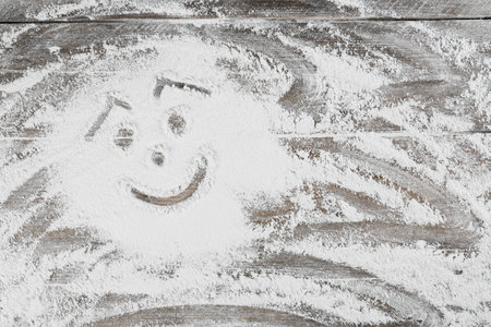 Smiling face made with flour on wooden table, top view. Space for textの写真素材