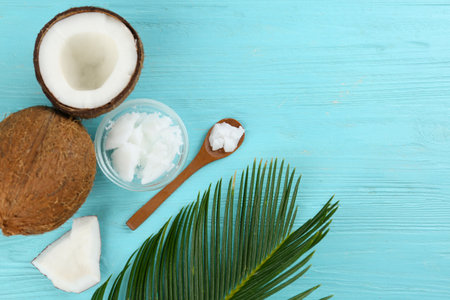Flat lay composition with organic coconut oil on light blue wooden table. healthy cooking