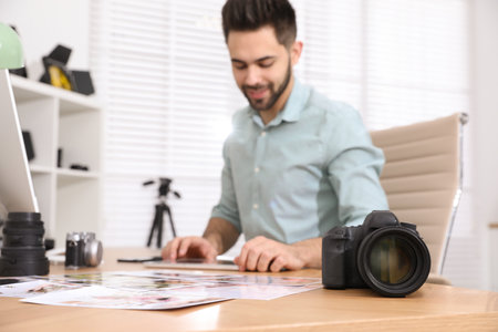 Professional photographer working at table in office, focus on cameraの写真素材