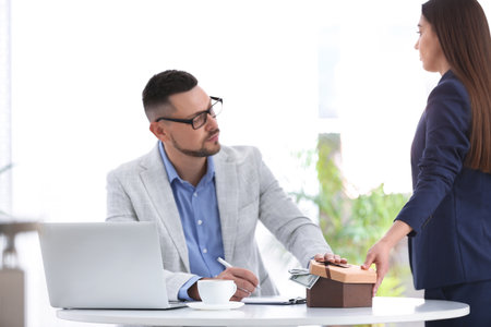 Woman giving bribe to man at table indoors