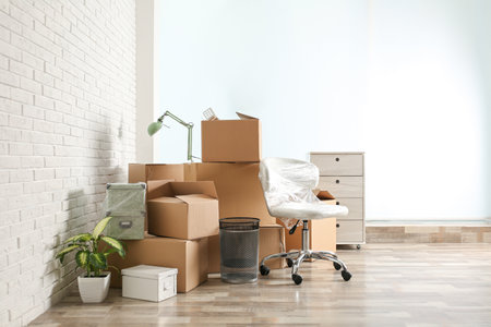 Moving boxes and stuff near white brick wall in room