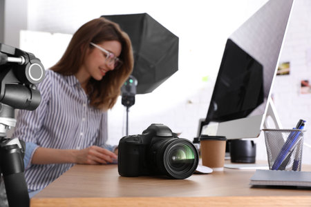 Professional photographer working at table in office, focus on camera