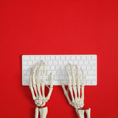 Human skeleton using computer keyboard on red background, top view. Space for textの写真素材