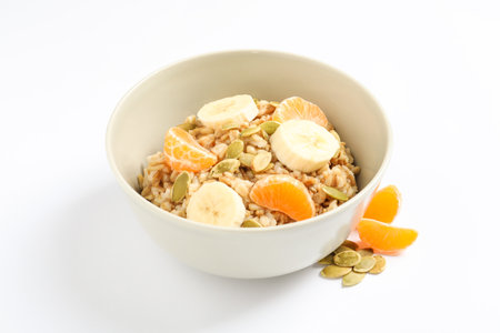 Tasty oatmeal with fruits and pumpkin seeds on white background. healthy breakfastの写真素材