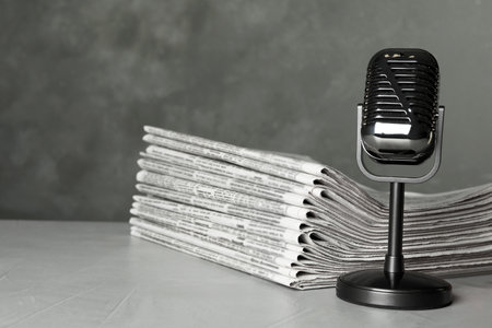 Newspapers and vintage microphone on light gray stone table. Journalist's workの写真素材