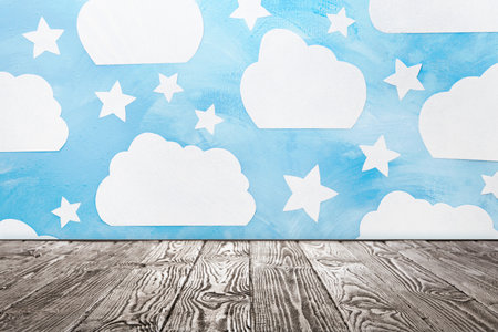Wooden table near wall with painted clouds and stars. Idea for baby room interior design