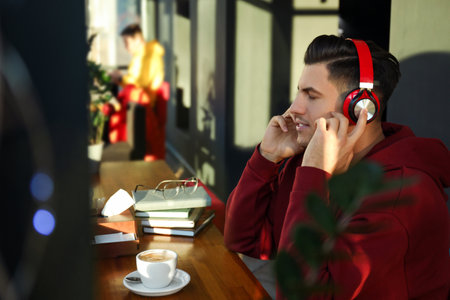Man listening to audiobook at table in cafeの写真素材