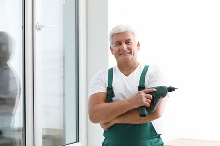 Mature repairman with electric screwdriver near plastic window indoorsの写真素材