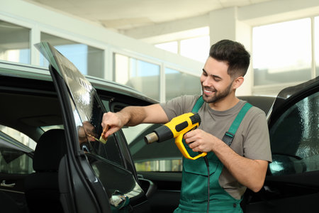Worker tinting car window with heat gun in workshopの写真素材