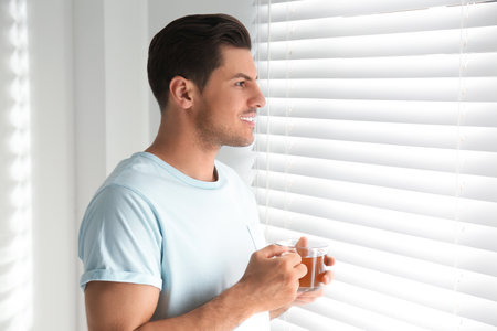 Man with cup of tea near window. Lazy morningの写真素材