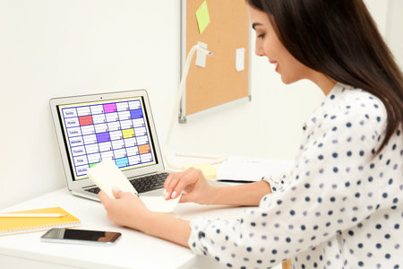 Young woman planning her schedule with calendar app on laptop in officeの写真素材