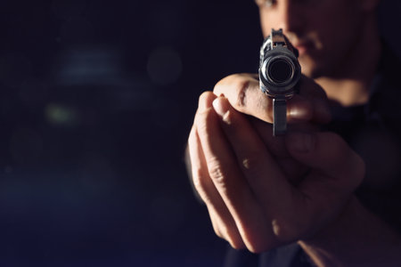 Professional killer with gun on black background, closeup. Space for textの写真素材