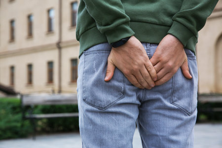 Man suffering from hemorrhoid pain outdoors, back viewの写真素材