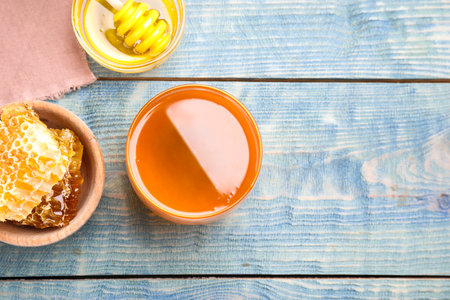 Tasty honey on light blue wooden table, flat lay. Space for textの写真素材