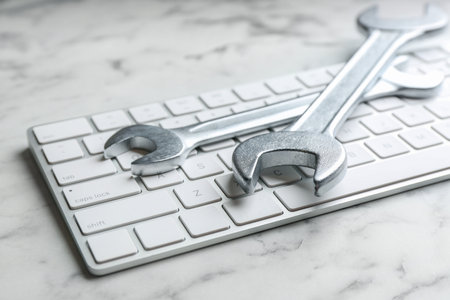 Keyboard and spanners on white marble table, closeup. Concept of technical supportの写真素材