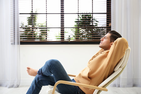 Attractive man relaxing in armchair near window at homeの写真素材