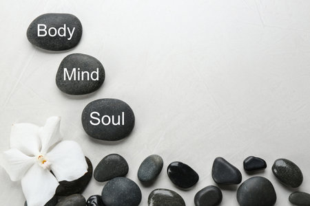 Stones with words MIND, BODY, SOUL on light background, top view and space for text. Zen lifestyleの写真素材