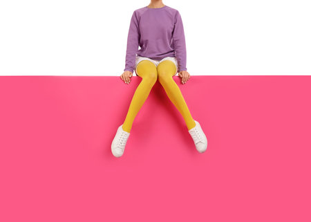 Woman wearing yellow tights and stylish shoes sitting on color background, closeupの写真素材