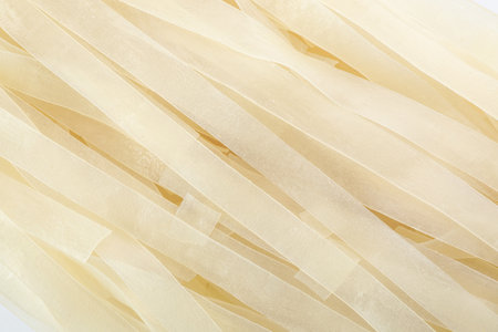 Raw rice noodles as background, closeup view
