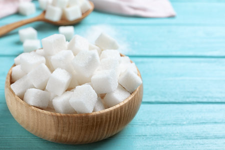 Refined sugar cubes in bowl on blue wooden tableの写真素材
