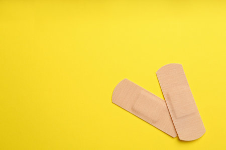 Sticking plasters on yellow background, top view. Space for textの写真素材