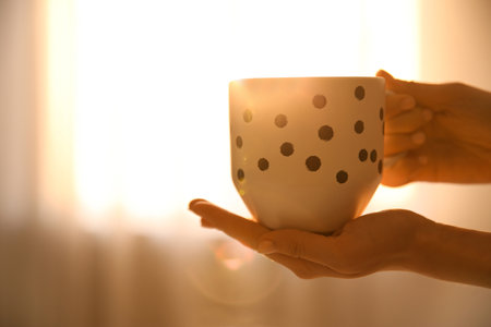 Woman holding cup of drink on blurred background, closeup. Lazy morningの写真素材